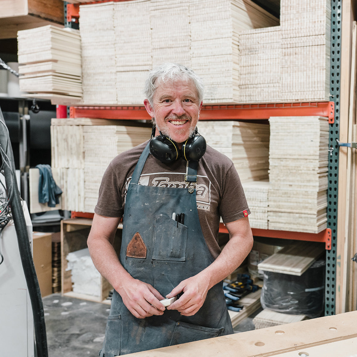 Cormac Bourke smiles in front of a stack of raw cores at the Wagner Custom Ski Factory.